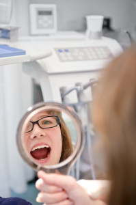 Frau schaut in den Spiegel beim Zahnarzt